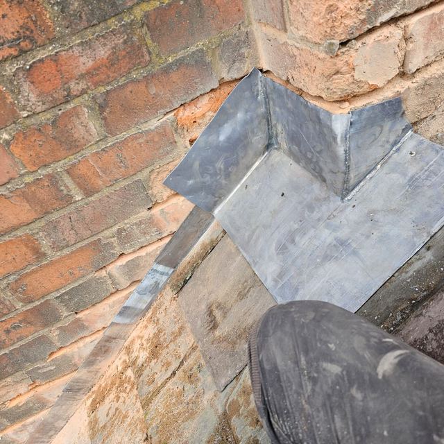 New lead saddle where a roof meets a brick wall