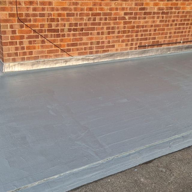 Grey flat roof meeting the house wall with a lead flashing