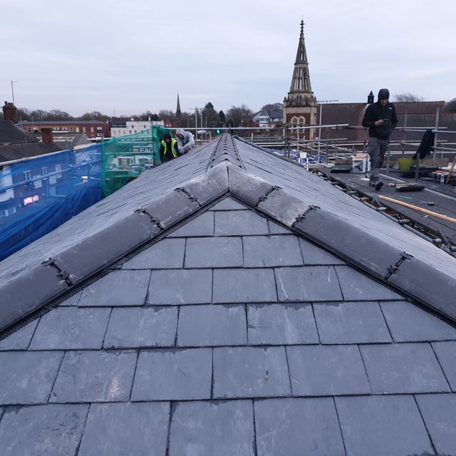 New slate roof and ridge, with a church spire behind